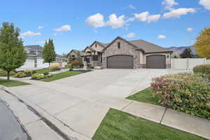 French country inspired facade with an attached garage, driveway, stucco siding, and stone siding