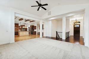 Unfurnished living room featuring a chandelier, light colored carpet, and ceiling fan