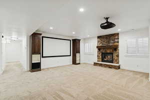 Home theater featuring light colored carpet, a fireplace, and recessed lighting