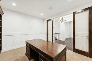 Office space featuring recessed lighting, light carpet, a decorative wall, and wainscoting
