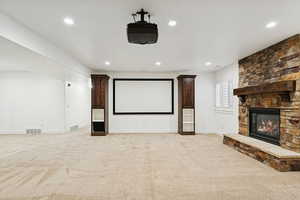Home theater room featuring light carpet, recessed lighting, and a fireplace