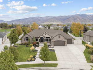 French country style house with stone siding, concrete driveway, a garage, and a mountain view