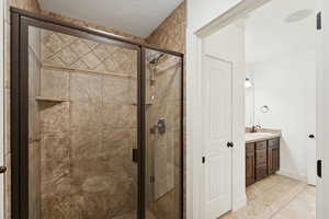 Bathroom with vanity, light tile patterned floors, and a stall shower