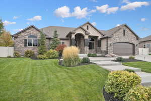 View of front facade featuring stone siding, stucco siding, concrete driveway, and a gate
