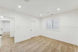 Unfurnished room with wainscoting, light carpet, and recessed lighting