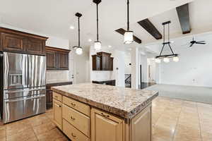 Kitchen featuring stainless steel fridge with ice dispenser, decorative light fixtures, beamed ceiling, a kitchen island, and open floor plan