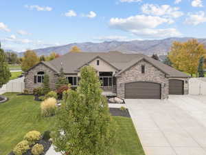 French country style house with a garage, a mountain view, and stone siding