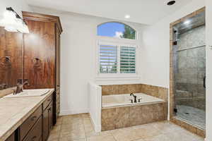 Bathroom featuring vanity, a bath, light tile patterned flooring, a shower stall, and recessed lighting