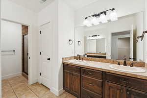 Bathroom featuring double vanity, light tile patterned flooring, and a shower stall