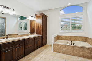 Bathroom with double vanity, a bath, light tile patterned floors, and a tile shower
