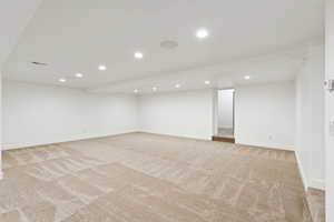 Finished below grade area with light colored carpet and recessed lighting