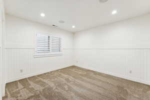 Carpeted empty room with wainscoting and recessed lighting