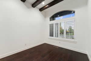 Empty room featuring beam ceiling and dark wood-style floors