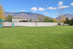 Fenced backyard with a mountain view and a playground