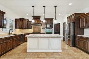 Kitchen featuring dark brown cabinetry, tasteful backsplash, stainless steel appliances, decorative light fixtures, and white cabinets