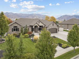 French country inspired facade with stone siding, a mountain view, concrete driveway, and a garage