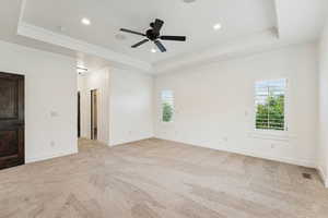 Unfurnished room featuring a tray ceiling, plenty of natural light, light carpet, recessed lighting, and crown molding