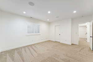 Unfurnished bedroom with light carpet and recessed lighting
