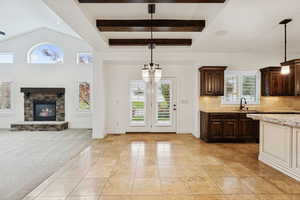 Kitchen featuring dark brown cabinetry, light tile patterned flooring, open floor plan, backsplash, and a stone fireplace