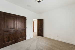 Unfurnished bedroom with carpet flooring and baseboards