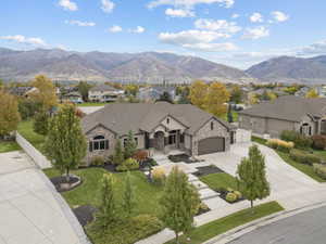 View of front of property featuring stone siding, driveway, a mountain view, an attached garage, and a residential view