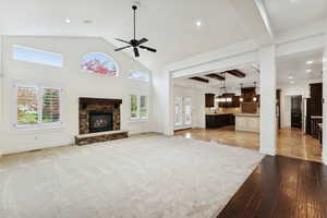 Unfurnished living room with beamed ceiling, a stone fireplace, a ceiling fan, light wood-style floors, and recessed lighting