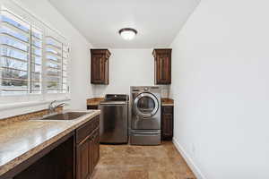 Laundry area with cabinet space, washing machine and dryer, and light stone finish floors