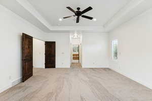 Unfurnished bedroom featuring light carpet, a tray ceiling, crown molding, ceiling fan, and recessed lighting