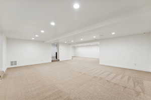 Finished below grade area with recessed lighting and light colored carpet