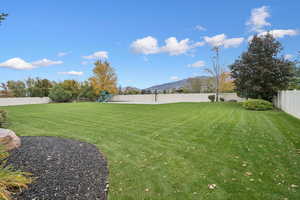 Fenced backyard with a mountain view and a playground