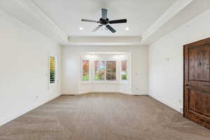 Unfurnished room featuring light colored carpet, a raised ceiling, recessed lighting, ceiling fan, and crown molding