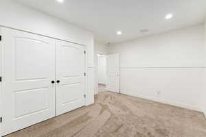 Unfurnished bedroom featuring light carpet, recessed lighting, and a closet