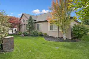 View of home's exterior with stucco siding, a yard, and a shingled roof