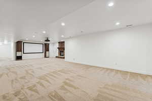 Cinema room with recessed lighting, a stone fireplace, and light carpet