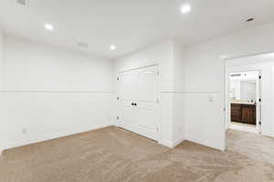 Empty room featuring light carpet, recessed lighting, and wainscoting