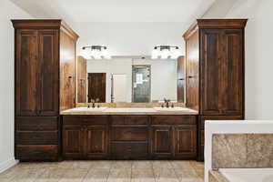 Bathroom with double vanity, light tile patterned floors, and a shower stall