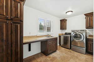 Washroom with cabinet space, separate washer and dryer, and light stone finish flooring