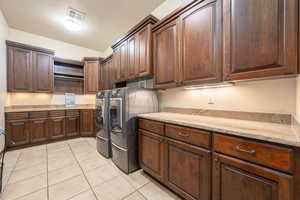 Laundry room with light tile patterned flooring, separate washer and dryer, and cabinet space