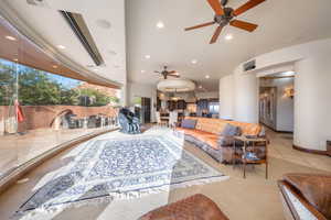 Carpeted living area with a ceiling fan, recessed lighting, and tile patterned floors