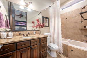 Full bath with ensuite bath, tiled shower / bath combo, vanity, backsplash, and a ceiling fan