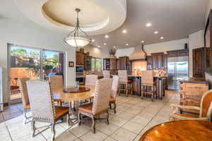 Dining area with a tray ceiling, recessed lighting, and light tile patterned floors