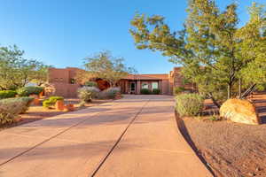 Pueblo revival-style home featuring driveway and stucco siding