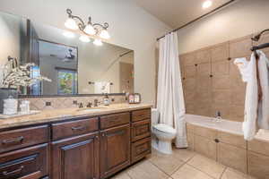 Full bathroom with vanity, tiled shower / bath, light tile patterned floors, and ceiling fan