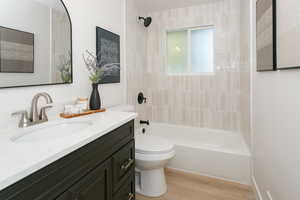 Full bathroom with washtub / shower combination, vanity, and light wood finished floors