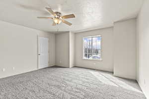 Carpeted spare room featuring a textured ceiling and a ceiling fan