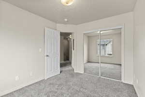 Unfurnished bedroom with carpet, a textured ceiling, and a closet
