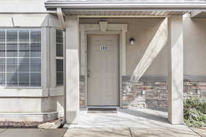 View of exterior entry with stone siding and covered porch