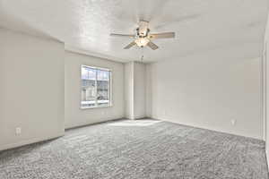 Unfurnished room featuring carpet flooring, a textured ceiling, and a ceiling fan