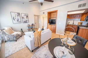 Living area with light tile patterned flooring, a ceiling fan, and lofted ceiling