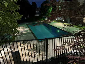 Pool at night with a community pool, a balcony, and a patio